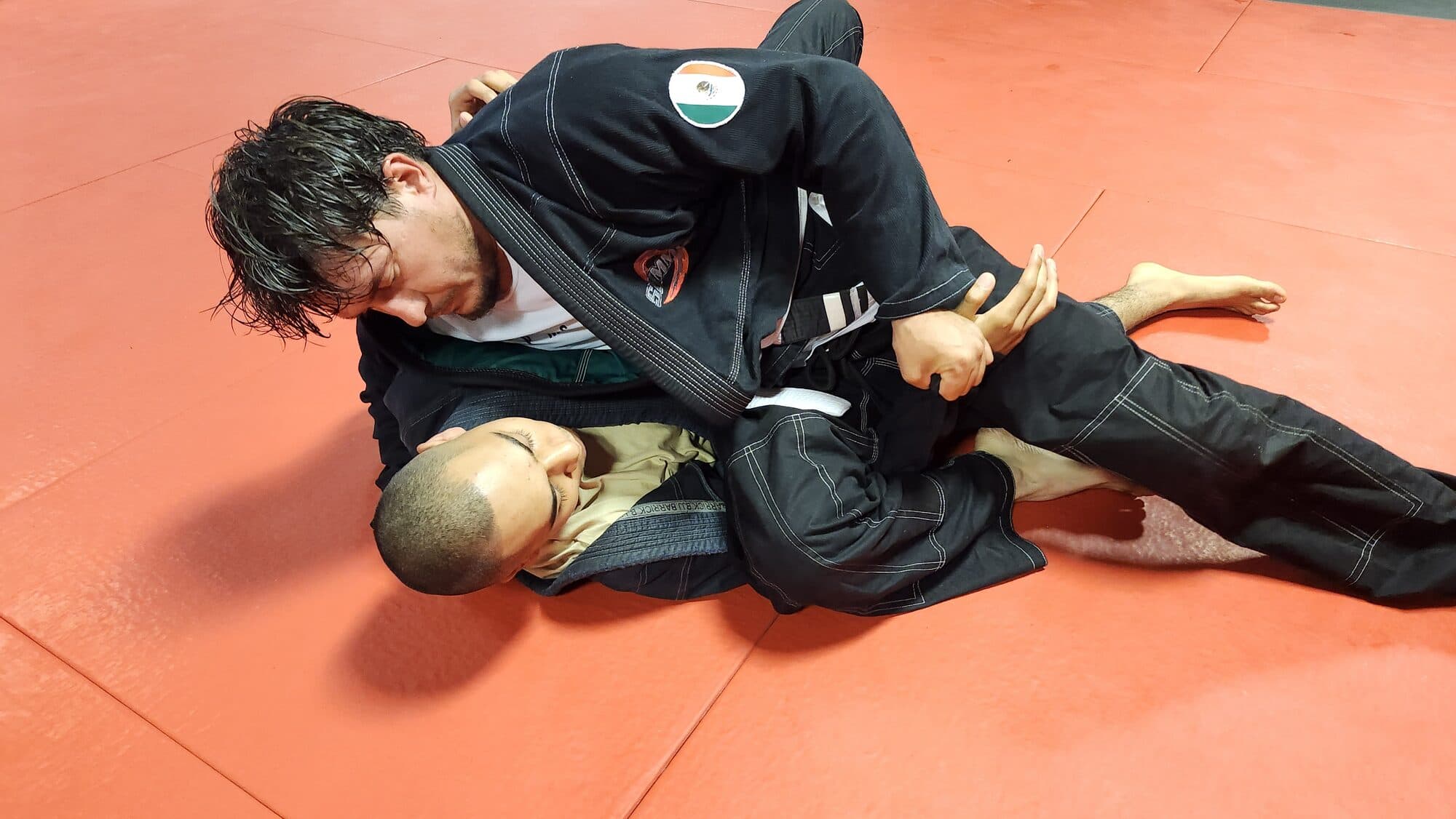 Two adult students drilling a gi Brazilian Jiu-Jitsu technique on the mats at Barrick BJJ