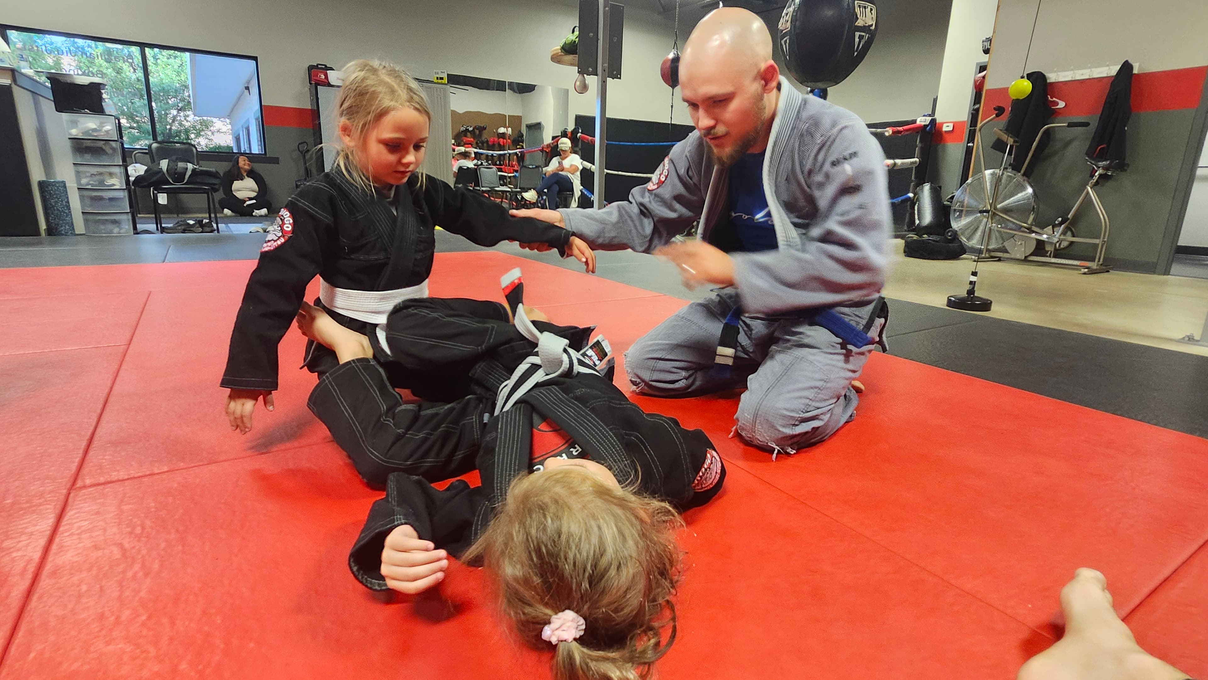 A young student working through a ground drill with a coach at Barrick BJJ