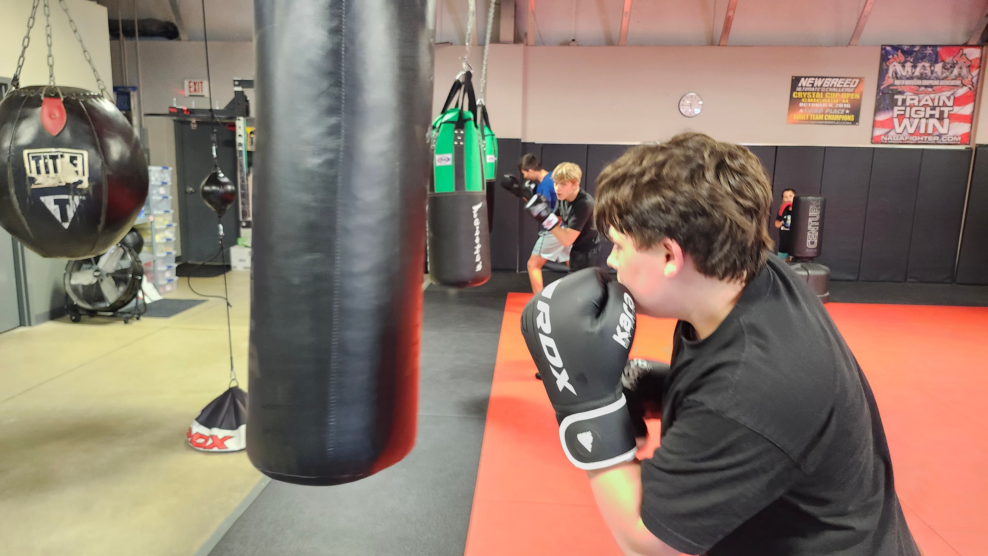 A teen boxing student practicing punches on a heavy bag