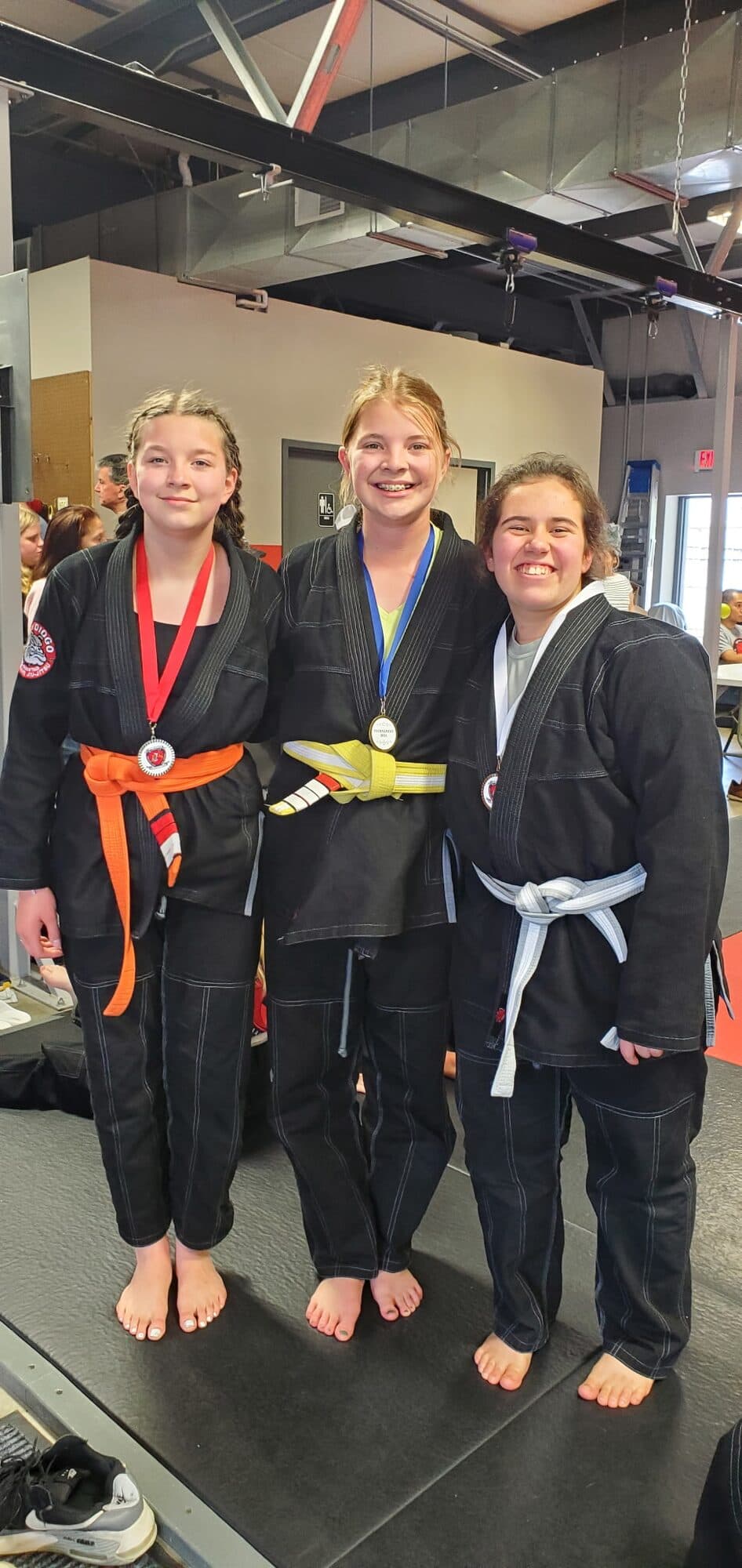 Three young Barrick BJJ students showing the medals they won at a jiu-jitsu tournament